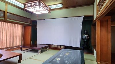 150インチのプロジェクタースクリーン完備 - KITAKYUBASE レンタルスペース 45平米の広々和室の古民家 レンタルスペースの設備の写真