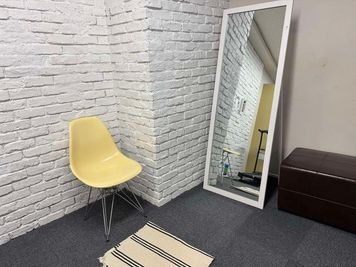 大きめの姿見の鏡、椅子があり更衣室としても使えるスペースです。床はプローリングカーペットです。壁はレンガ調の白壁です。撮影の背景としても使っていただけます。 - ヴィンテージ撮影スタジオ DOT2（ドットツー）の室内の写真