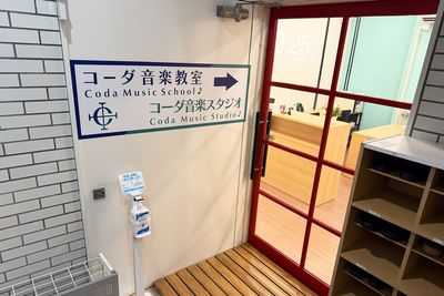入り口にはスタジオ案内サインと手指消毒、下足棚をご用意。土足を脱いで清潔な状態でお入りいただけます。 - コーダ音楽スタジオ クラシック向け防音スタジオ【Aスタジオ】の入口の写真