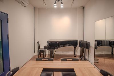 グランドピアノとテーブルを併用できるレイアウト。音楽理論の講座や受験対策レッスン、公開レッスンに便利です。 - コーダ音楽スタジオ クラシック向け防音スタジオ【Aスタジオ】の室内の写真