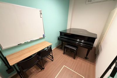 ホワイトボードと2名掛けテーブルを常設し、ソルフェージュや楽典指導にも対応できます。 - コーダ音楽スタジオ クラシック向け防音スタジオ【Bスタジオ】の室内の写真