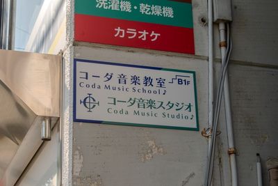 桂駅方面からは建物側面の案内看板が目印。「コーダ音楽スタジオ B1F」と表示されています。 - コーダ音楽スタジオ クラシック向け防音スタジオ【Bスタジオ】の外観の写真