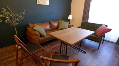 ゆったりとしたレザーソファがくつろぎの時間を演出。木目のテーブルと落ち着いたグリーンのソファは、ほっと心をほどくような空気感を作り出します。 - アトリウム池袋の室内の写真