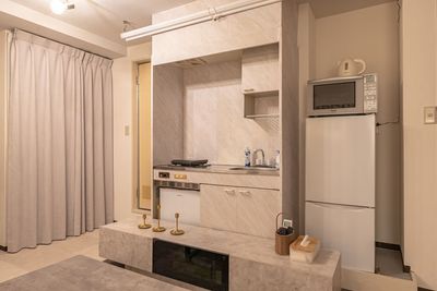 スクリーンを上げれば、キッチンがあります。
2ドアタイプの冷蔵庫には食材や、お祝いケーキも十分入ります。
電子レンジ、ケトルもあります。 - Private Screen Lounge なんばの室内の写真