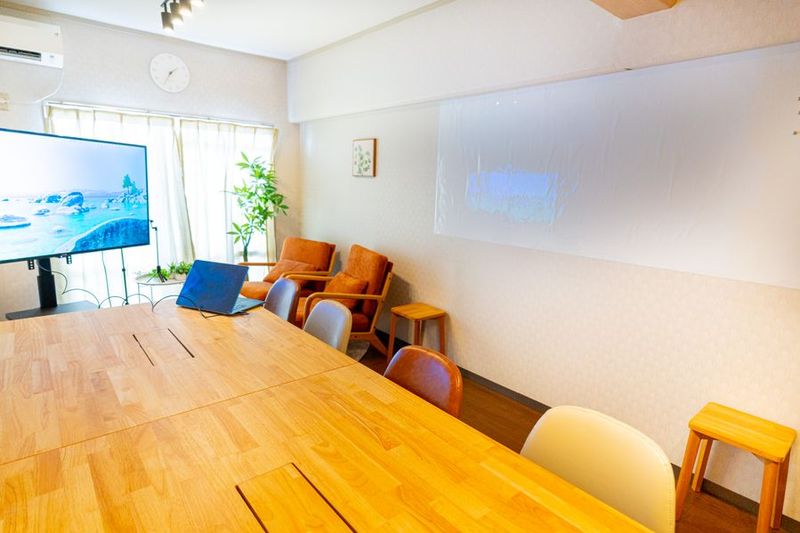 大きな木製テーブルとプロジェクタースクリーンを備えた会議室 - 千種レンタル会議室・テラスの室内の写真