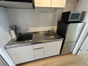 IHコンロ・冷蔵庫・電子レンジ付きのキッチン。※調理器具は各自お持ち込みください。 - Bed&City 北池袋 レンタルスペース 302号室｜大きなカウチソファでくつろげる完全個室の設備の写真