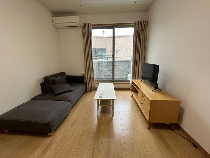 大きなカウチソファでゆったりくつろげるリビング。テレビも完備しています。 - Bed&City 北池袋 レンタルスペース 302号室｜大きなカウチソファでくつろげる完全個室の室内の写真