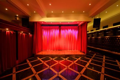 赤いカーテンに囲まれたステージ
奥のカーテンと、ステージ前のカーテンは電動カーテンです。
※ステージの大きさ（435mm×155mm×25mm） - SuNaBa 多目的レンタルスペースの室内の写真