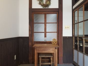 エントランスは4.6㎡(畳約３畳分)あり、広々とした空間です。木製のテーブルとイスを使って受付も可能です。 - 癒しの古民家Kyoto Knot レンタルスタジオの入口の写真