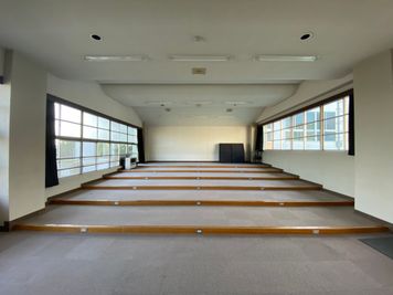 うしろの壁面全体をスクリーンとして使うこともできます。 - 八ヶ岳コモンズ シアターコモンズ（音楽教室）の室内の写真