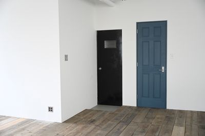 海を感じさせるノースブルーと船舶ハンドルがアクセントのトイレドアはウッドスペースにあるります - mo' better（モーベター） フォトスタジオの室内の写真