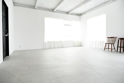 モルタル床のスペースは天井、壁、窓枠は全て白く、リネンのレースカーテンで光回りも良いシンプルな空間 - モーベター フォトスタジオの室内の写真