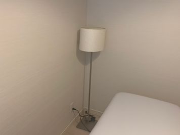 正面は天井からぶら下がりタイプのライトと、こちらのスタンドライトになります。どちらも暖色です。 - 貸会議室en.beaute 都立大学レンタルエステルームの設備の写真