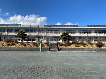 朝礼台や掲揚台ポール（3本）があります。 - 八ヶ岳コモンズ グランド（校庭）の室内の写真