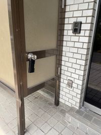 入り口左側にキーボックスがあり、この中にガラス扉の鍵が入っています。キーボックスがぶら下がっている扉は入り口ではありませんのでご注意ください。 - ハイツシマ 楽器練習、ヨガ、簡単なダンスや体操、発声練習などにの入口の写真