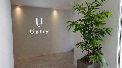 入り口にはロゴと観葉植物があります。 - Unity Unity 個室レンタルサロン ルームEの入口の写真