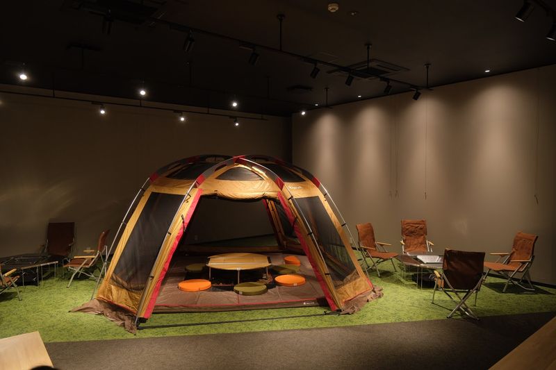 スノーピークのテントやジカロテーブルがセットされた非日常の空間でテレワークや勉強、ワークショップが体験できます。 - Kochi Startup BASE コミュニティスペースの室内の写真