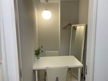 穏やかな照明、テーブルとイス２脚、姿見やハンガー、コンセント２口あります。 - セルフホワイトニング専門店ホワイトニング明石 ホワイトニング明石の鍵付き個室の設備の写真