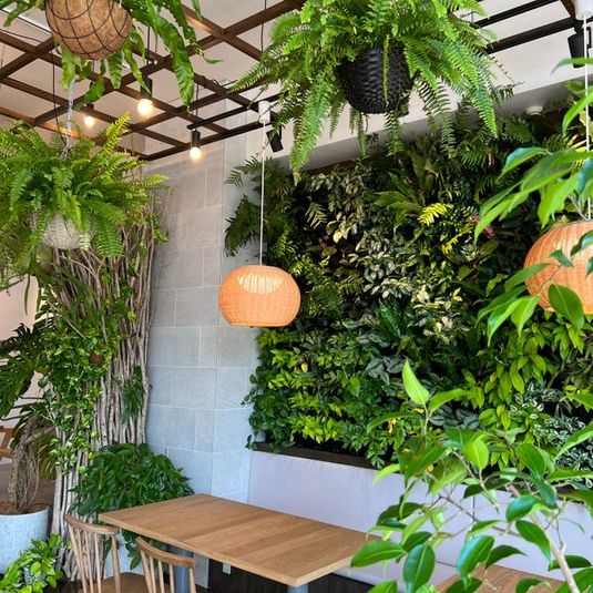 4人掛けのテーブル2つ。背景に使える植物の大きな壁面緑化。 - GREEN＆CAFE（グリーンアンドカフェ） 緑がたくさんの多目的スペースの室内の写真