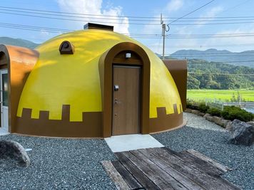 ドームには天窓があり、入り口は2カ所、窓は3つ。外観は黄色で、ラウンドマーク的な存在。 - 糸島ドームハウスの外観の写真