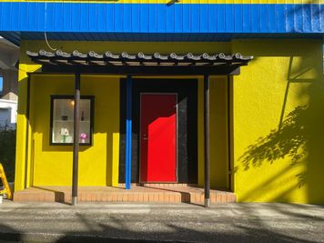 青と黄色の外壁に赤い扉の特徴的な建物です。 - スタジオ　グルッペの入口の写真