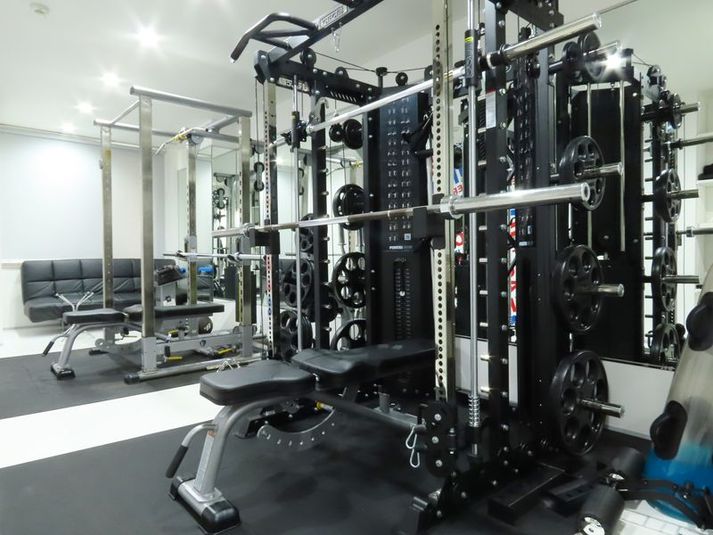 トレーニングスペースにはパワーラックとオールインワンラックが一つずつ。20kgバーとアジャスタブルベンチ×２。パワーブロック50lb×１。 - 株式会社MUSCLE・BODY・MAKE レンタルジムの室内の写真