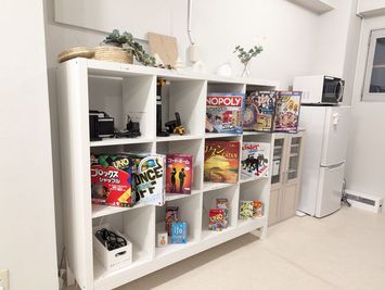 キャビネットと20種類弱のボードゲームと食器棚、冷蔵庫、電子レンジ - rental lounge御茶ノ水の設備の写真