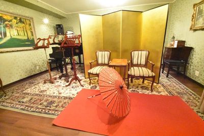 洋風なスタジオ内に金屏風と赤い毛氈、赤い和傘を配置。対談企画やCMにも最適な撮影スポットです。 - 撮影スタジオ　こひなあた 金屏風と金の壁紙の写真スタジオの室内の写真