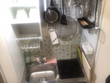 おおよそ必要なキッチン用品はそろっています。
右下がIH、
左上の棚にグラス6個、角平皿6枚、角小深皿6枚
右上に、スプーン6フォーク6箸6膳
右下にまな板複数 - 【遊び基地＆会議スペース】DECO新宿3丁目 24h🌈1名＆キレイ好き女性限定【新宿】⭕️繁華街ど真ん中❣の室内の写真