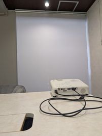 降ろしたブラインドに、プロジェクターを使用することで、画面の共有ができ会議や商談が行いやすくなります。 - Executive Suite Lounge 麹町 貸し会議室 「milk tea」の設備の写真