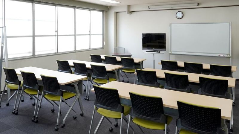 スクール形式　18名着席可能。全面に広がる窓からの光で明るく開放的な会議室。セミナーや会議などにぴったりな会場です。 - ミヤケインダストリー会議室 第一会議室 (貸会議室/セミナー会場)の室内の写真