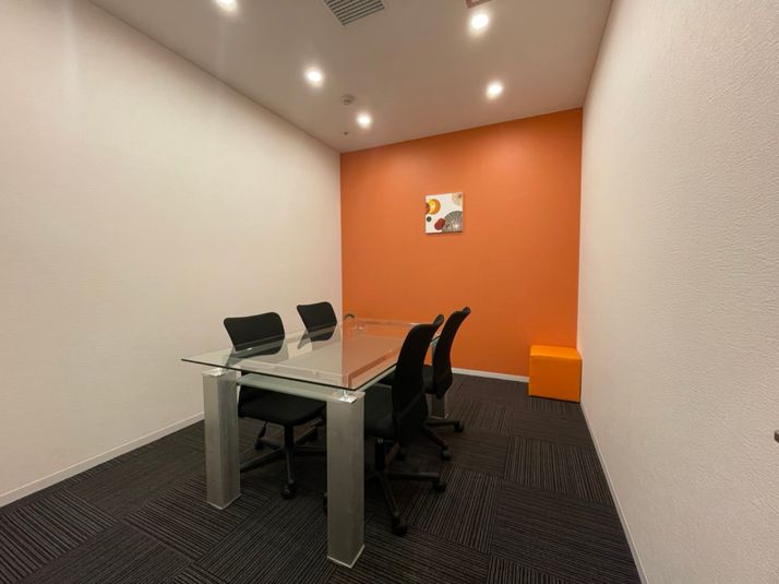 オレンジのアクセントカラーがおしゃれな個室です。ミーティングや勉強会の他、フリーWi-Fiを完備しておりますのでWEB会議にも最適です。 - シェアオフィスURL仙台駅東口 個室（オレンジ）の室内の写真